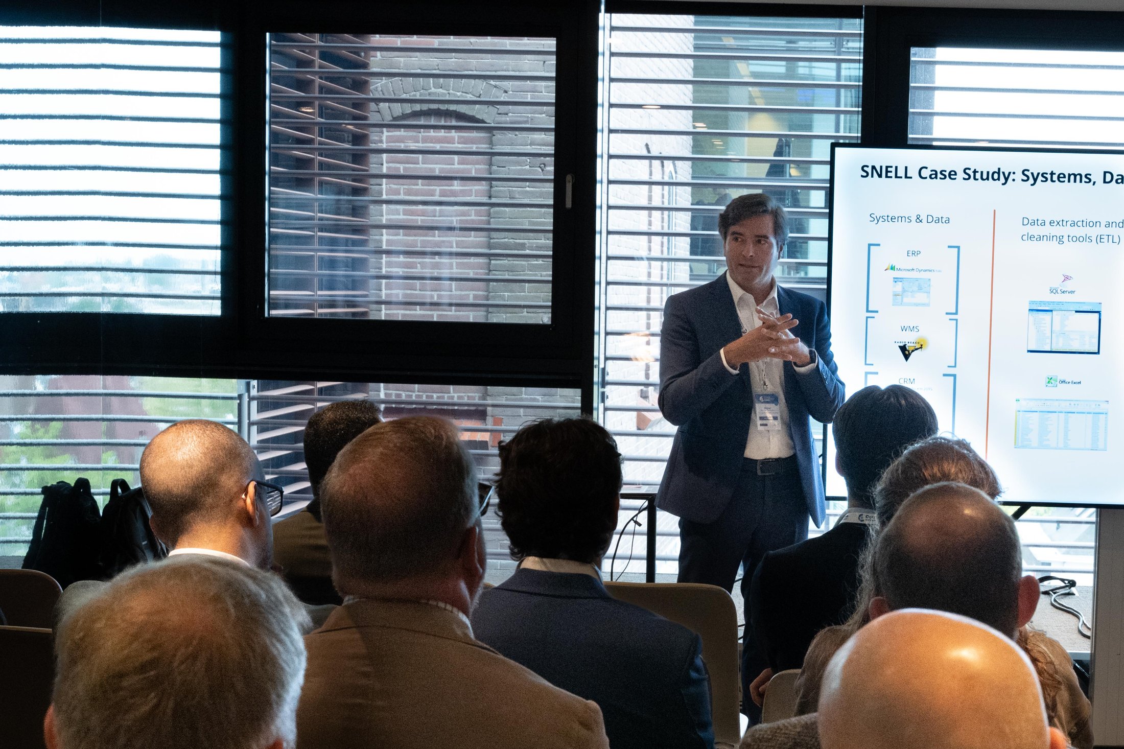 Miguel Guimarães a apresentar na The Costing Conference, em Amesterdão, junto a um ecrã com o slide do case study de distribuição SNELL.