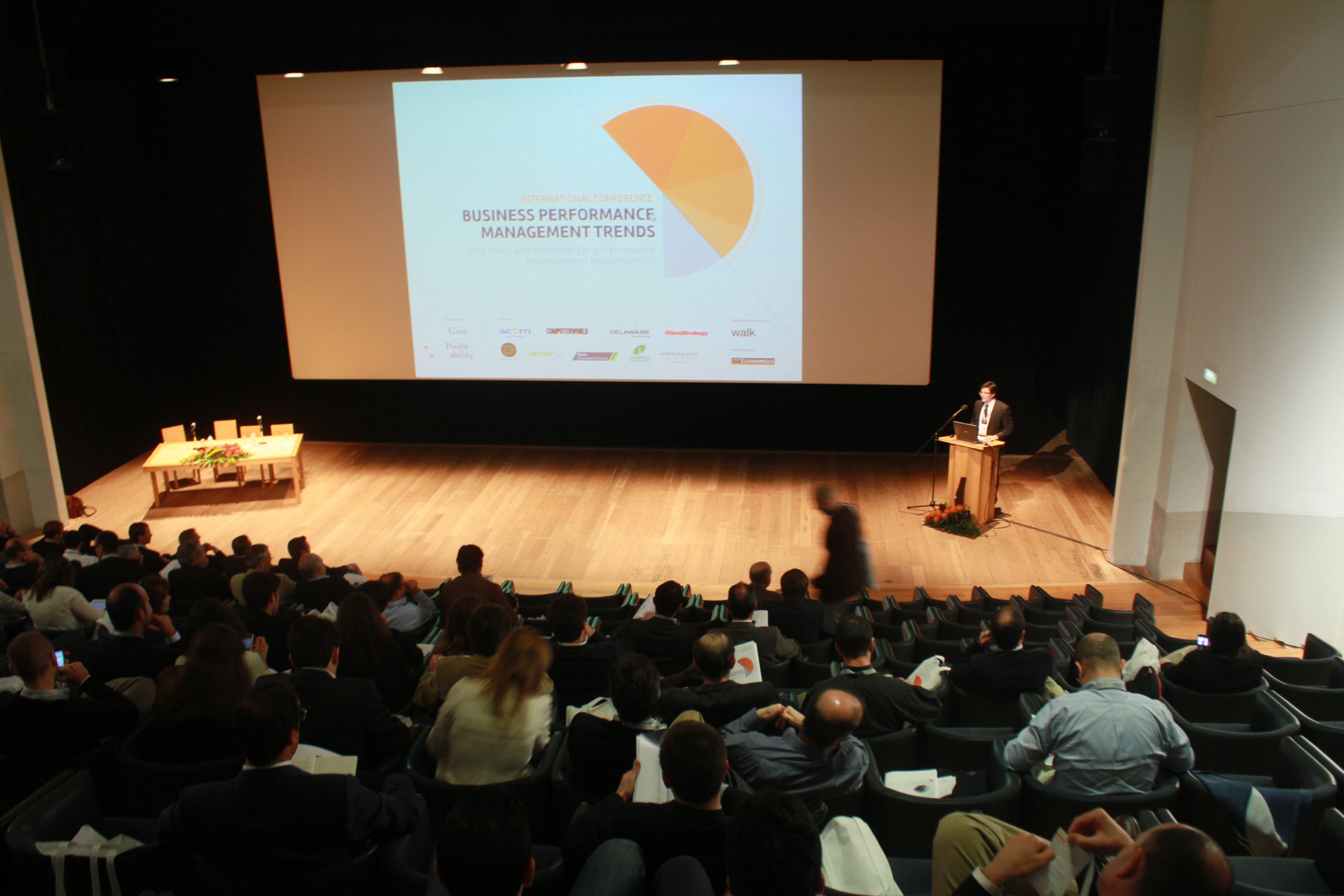 A full Serralves auditorium during the Business Performance Management Trends conference, with the speaker at the podium and the partner logos projected on the main screen.